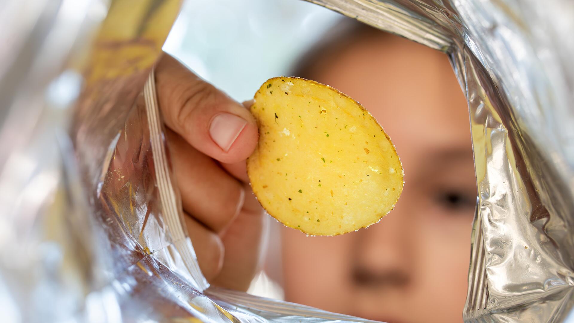 Chips aus der Tüte: Ein Kind greift zu. 
