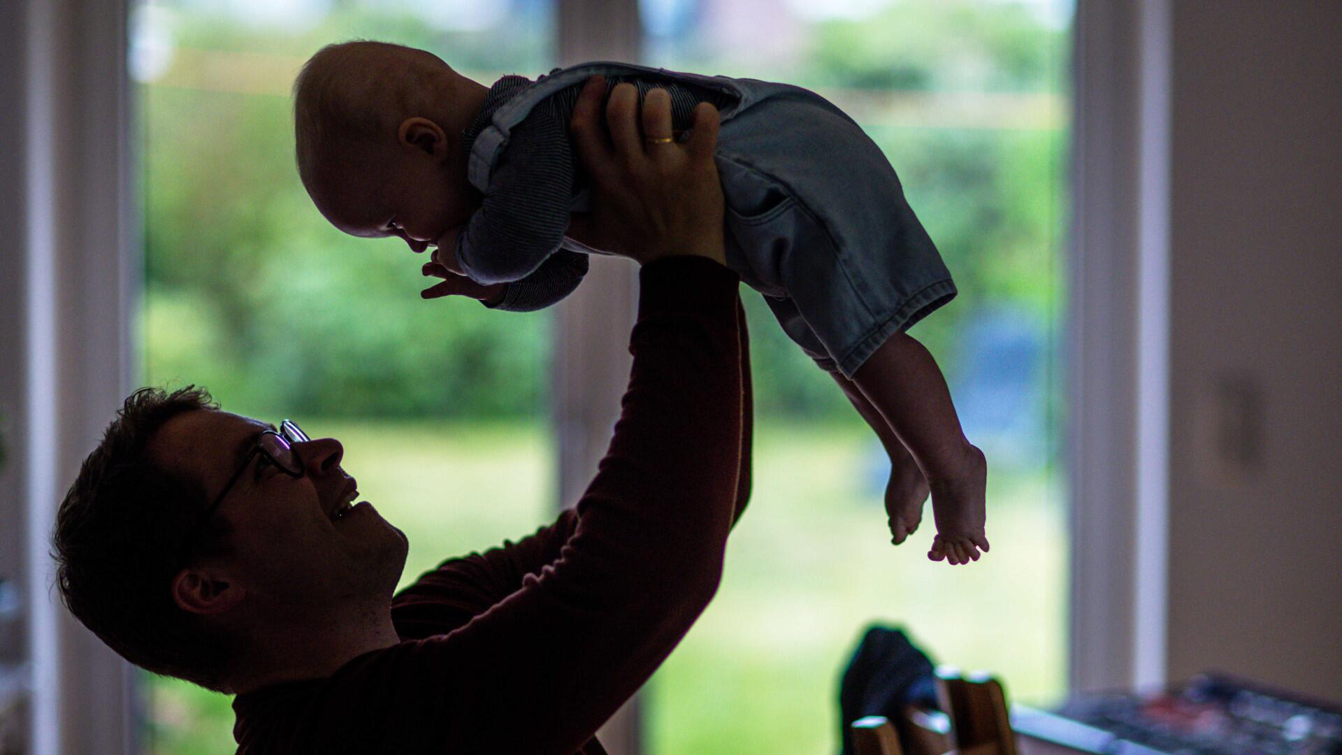 Ein Baby wird von einem Mann nach oben gehalten
