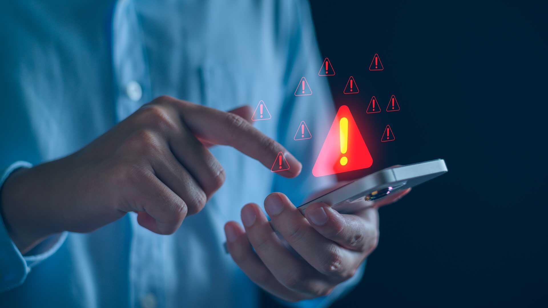 Hand hält Handy, Warnsignal in rot leuchtet darüber