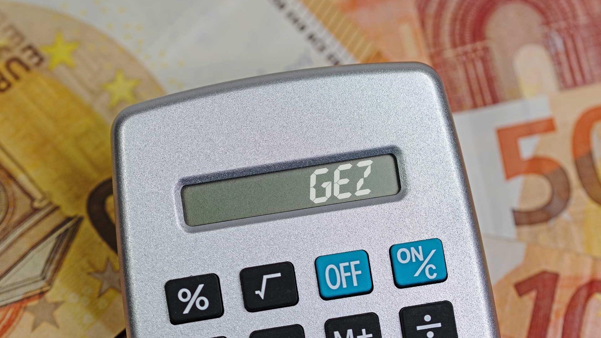 Taschenrechner mit Aufschrift "GEZ" liegt auf Geld