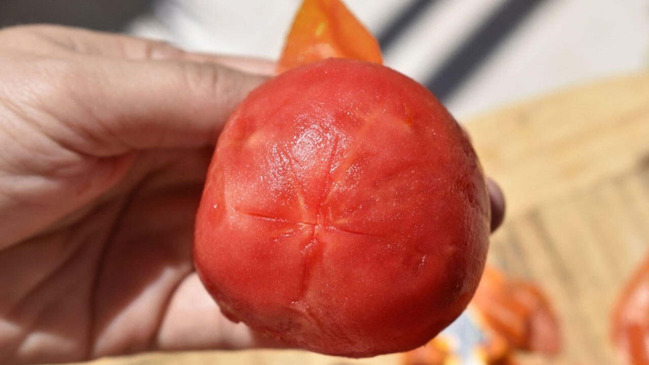 Wenn Sie die Tomate kreuzweise eingeschnitten haben, können Sie die Haut nach dem Kochen einfach abziehen.